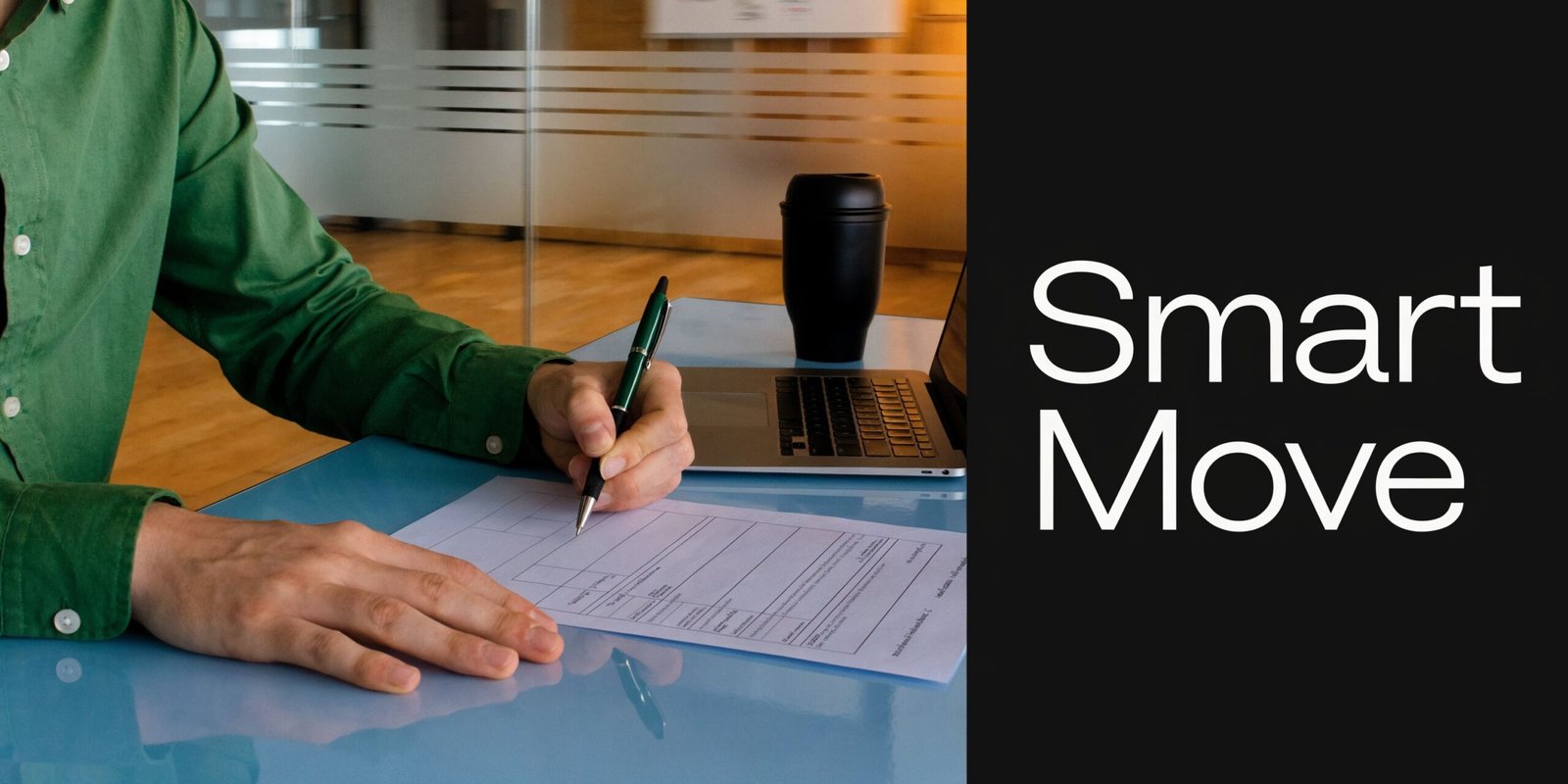 A person in a green shirt sits at a desk signing a document next to a laptop.